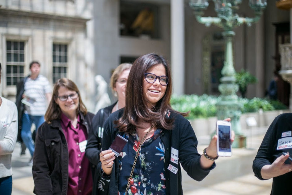 A woman holds up a phone. Embrace the smartphone revolution and Instagram for team building!