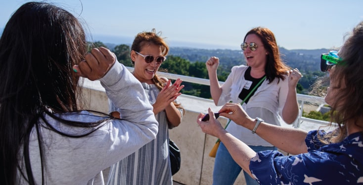 A group doing fun outdoor team building activities with four women cheering.
